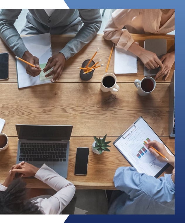 A group of people sitting at a table with papers and cups.